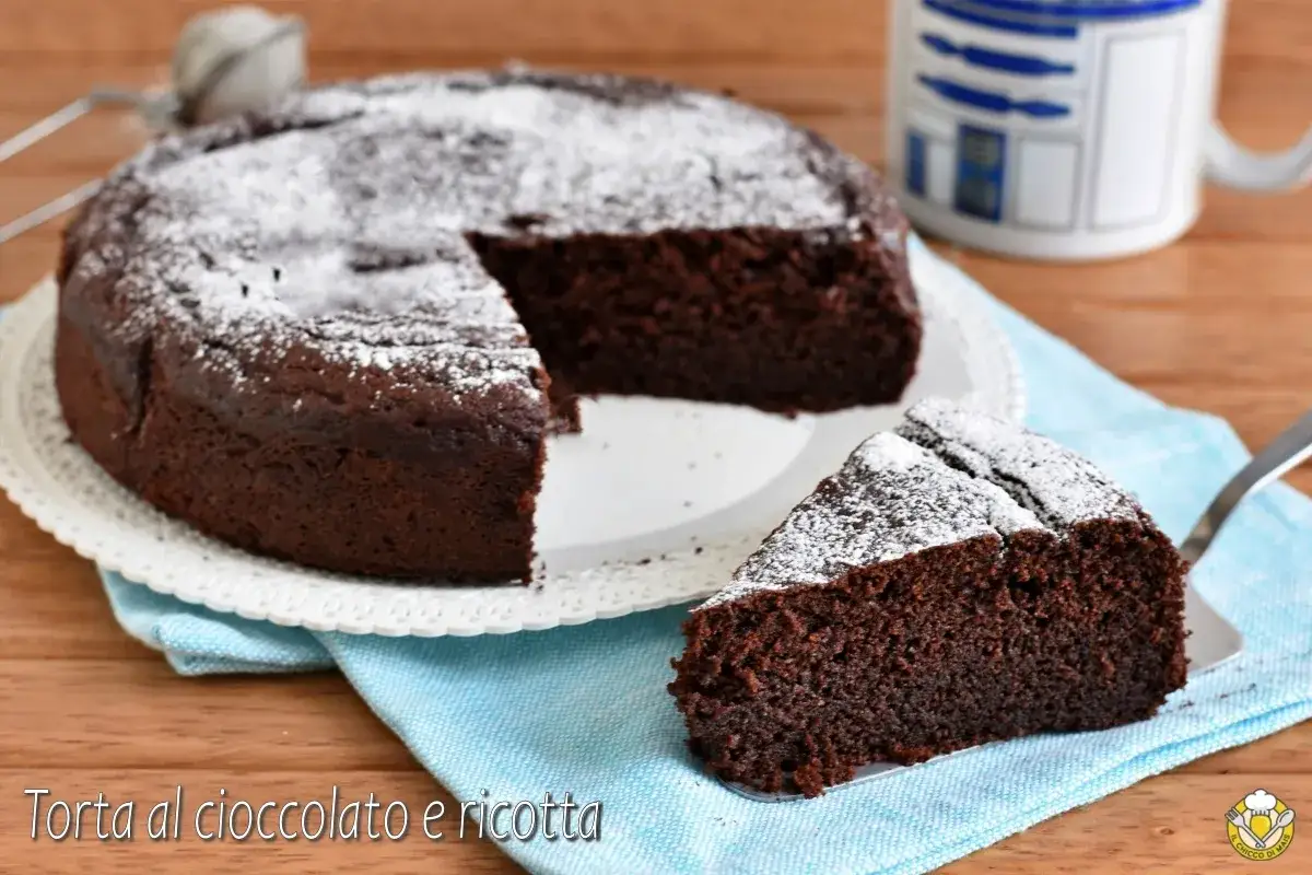 Torta al cioccolato e ricotta, soffice e golosa, spolverata di zucchero a velo. Una fetta attende di essere gustata.