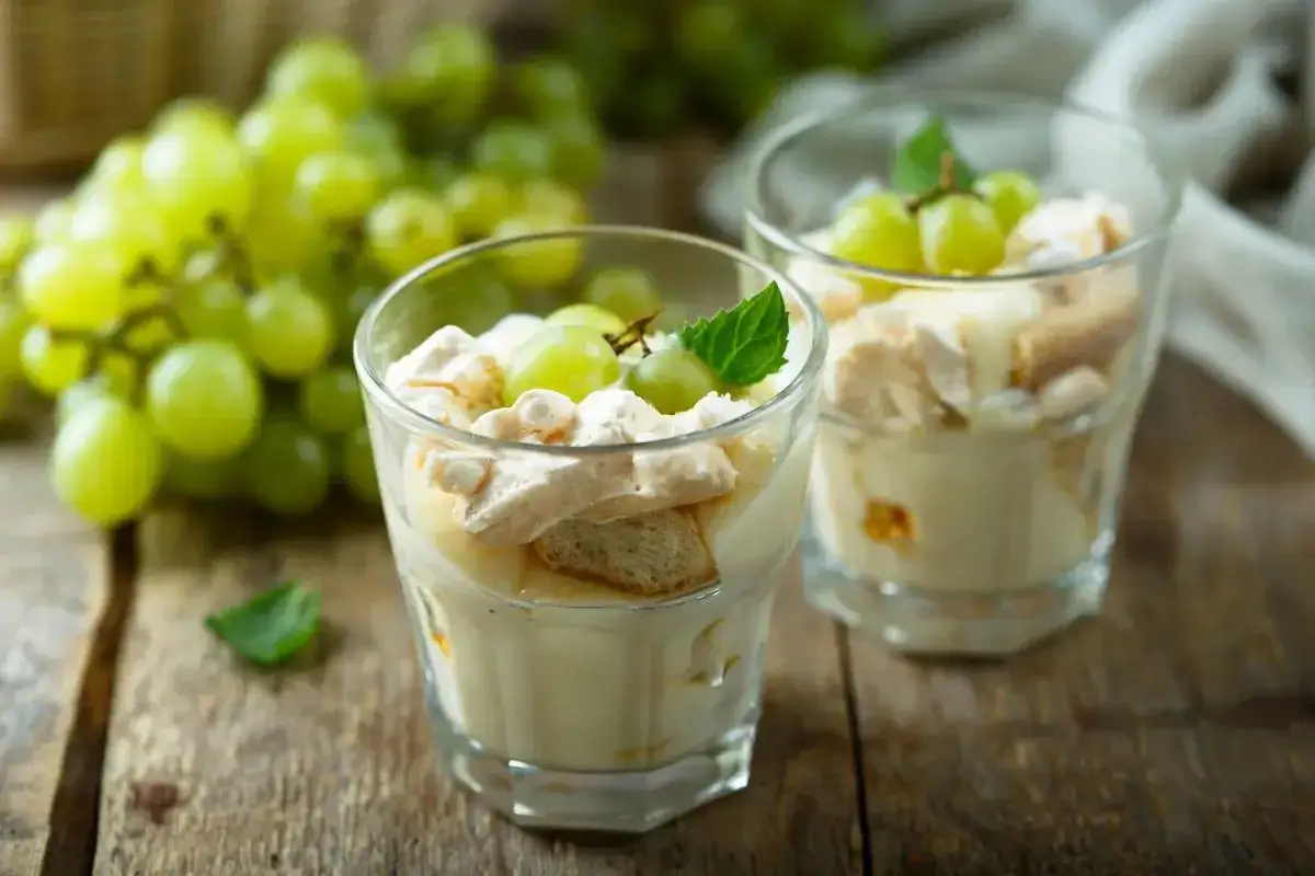 Deliziosa mousse di ricotta al bicchiere, guarnita con uva fresca e meringa croccante, un dolce leggero e invitante.