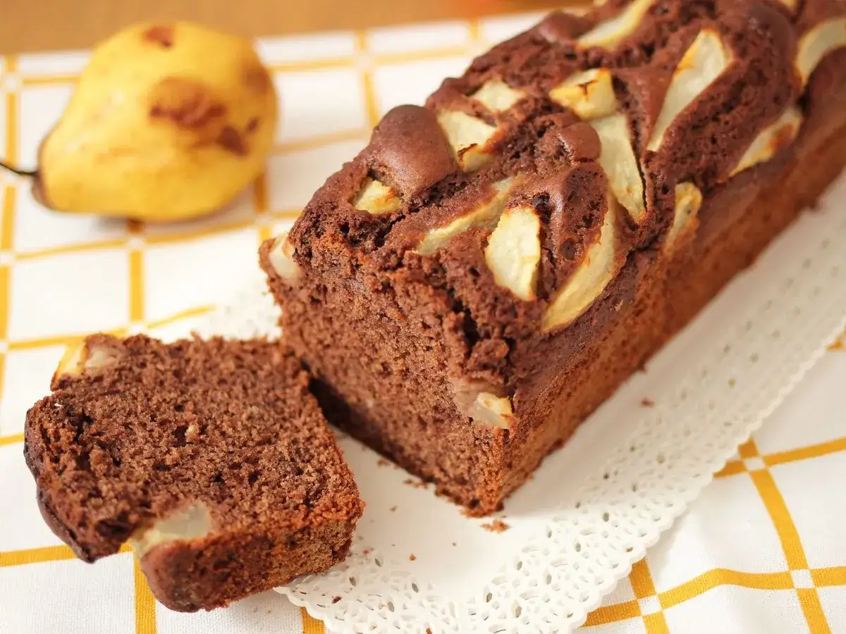Delizioso plumcake al cioccolato con pere, una fetta tagliata mostra la morbidezza e i pezzi di frutta.
