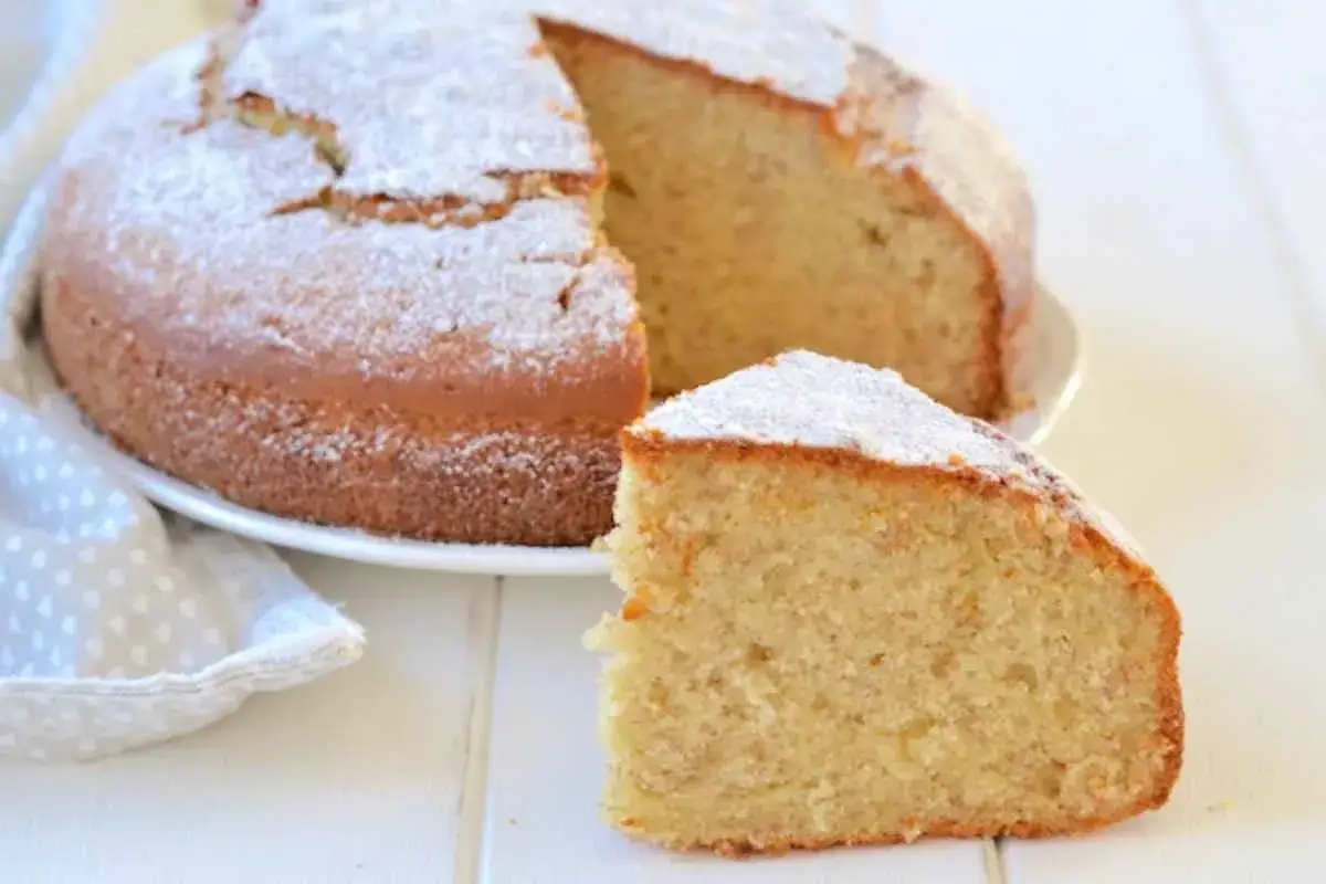 Un soffice plumcake alla banana, spolverato di zucchero a velo, con una fetta tagliata per mostrare la sua morbidezza.