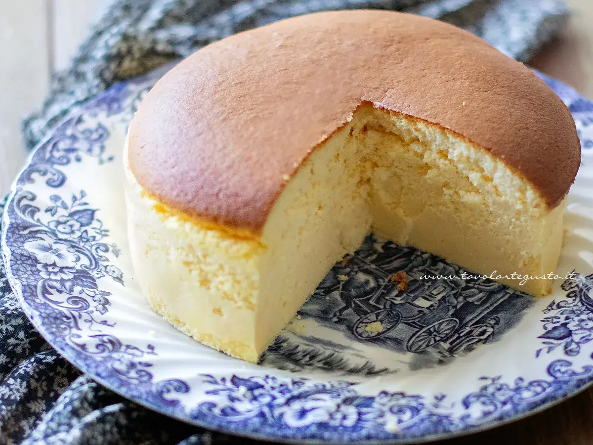 Una soffice torta al cotone, dorata in superficie e chiara all'interno, servita su un piatto decorato con un carretto.