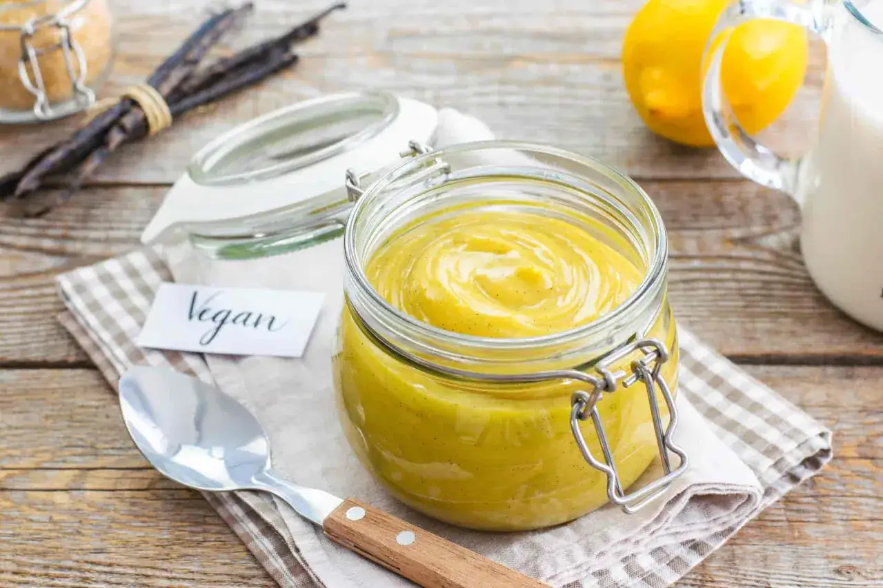 Vasetto di crema pasticcera vegana, con vaniglia e limone sullo sfondo.