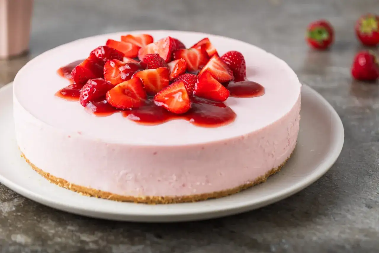 Delizioso cheesecake alle fragole, con fragole fresche e salsa rossa, su una base croccante.
