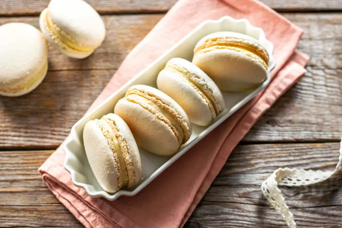 Macarons bianchi con ripieno cremoso, pronti per essere gustati. La ganache per macarons è il cuore di questi dolcetti perfetti.