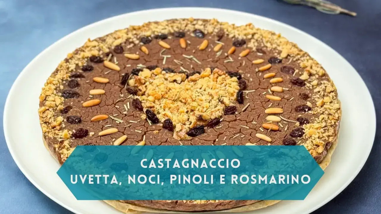 Castagnaccio morbido con uvetta, noci, pinoli e rosmarino, decorato al centro con un cuore di noci e briciole.