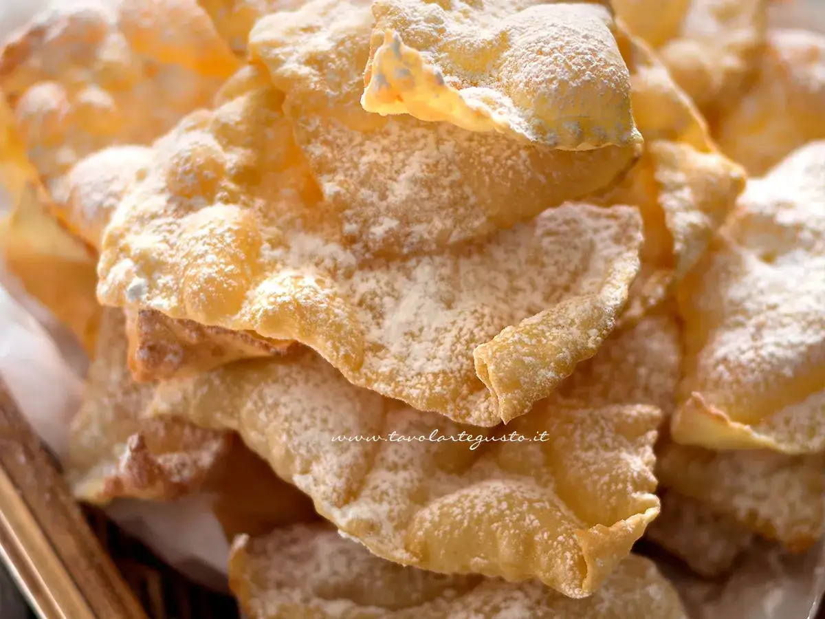 Chiacchiere croccanti, dolci e leggere, come quelle della ricetta della nonna, cosparse di zucchero a velo.