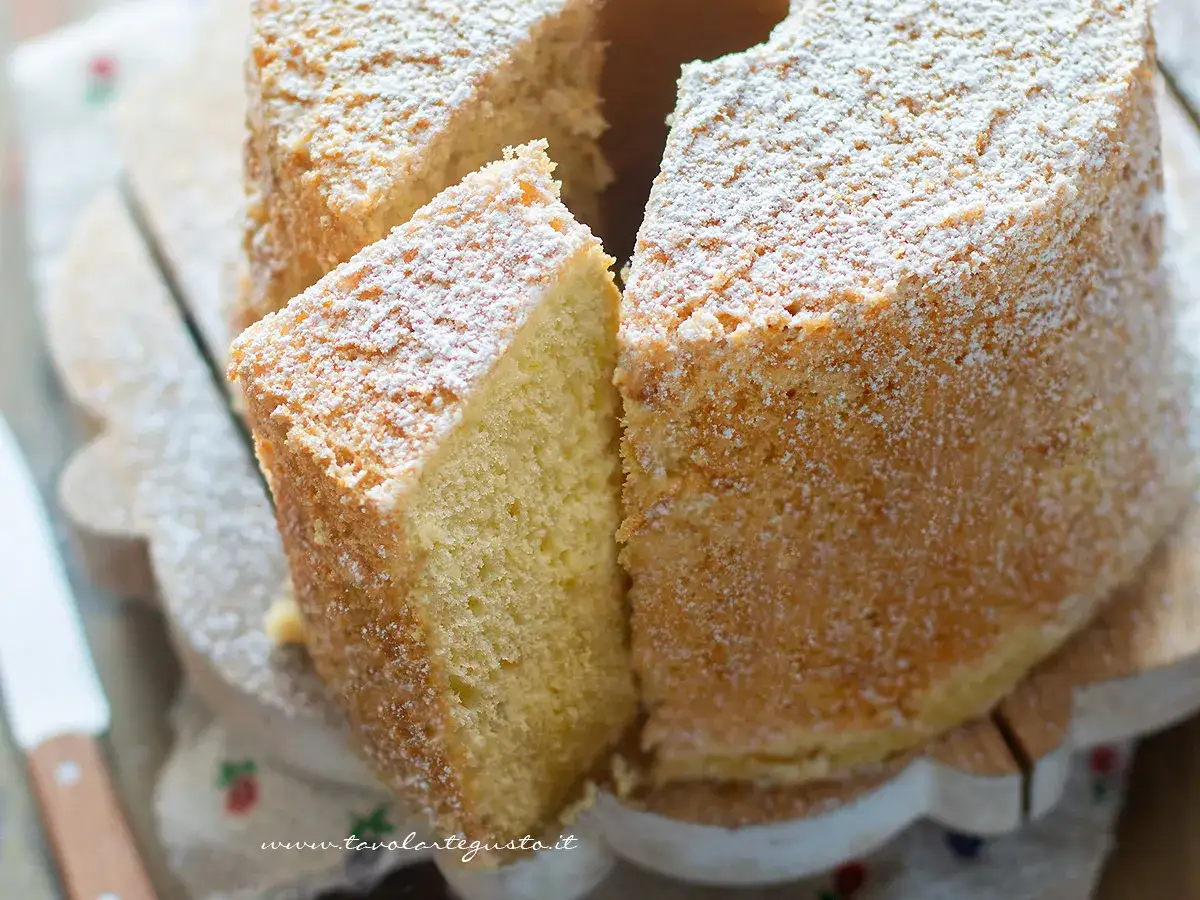 Una soffice torta alta, spolverata di zucchero a velo, con una fetta tagliata che invita ad assaggiarla.