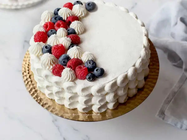Torta rotonda compleanno decorata con panna, lamponi e mirtilli. Un dolce perfetto per ogni festa.