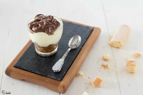 Delizioso bicchiere con crema al mascarpone e cacao, guarnito con una colata di cioccolato fondente.