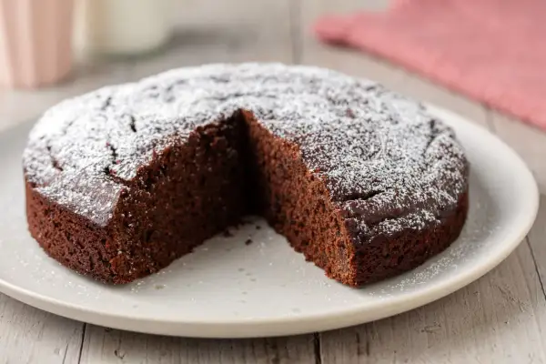 Una fetta è stata tolta da questa torta al cioccolato soffice, cosparsa di zucchero a velo.