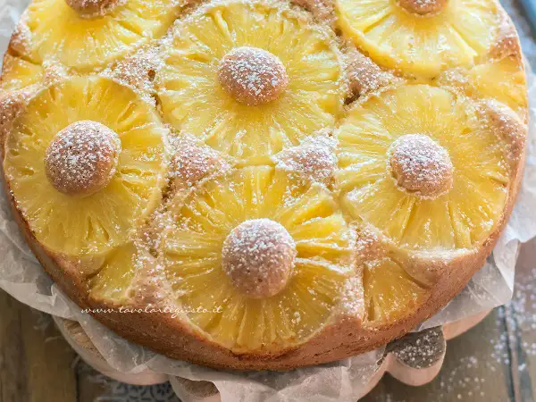 Torta ananas dorata e profumata, decorata con fette di ananas caramellato e spolverata di zucchero a velo.