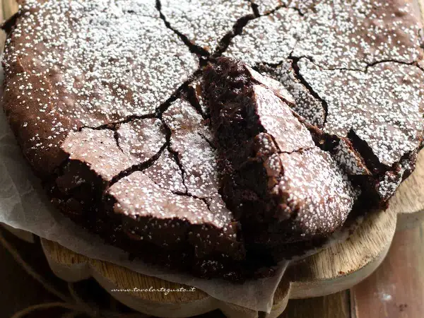 Deliziosi dolci con cioccolato fondente, una torta scura e umida con una crosta screpolata e cosparsa di zucchero a velo.