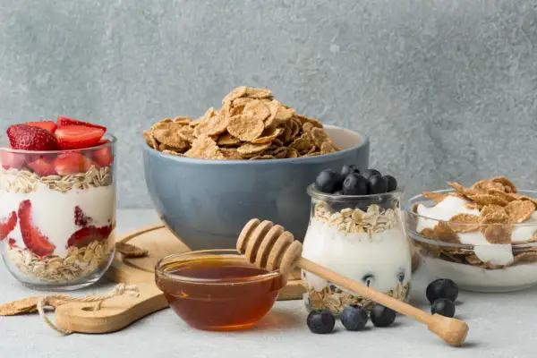 Colazione sana con cereali, yogurt, fragole e mirtilli. Un tocco di miele per dolcificare.