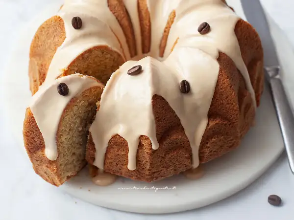 Deliziosa torta al caffè con glassa e chicchi di caffè, una fetta è stata tagliata per mostrare la morbidezza.