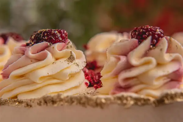 Deliziosi torte gelato e semifreddi decorati con crema rosa e gialla, lamponi e polvere dorata.