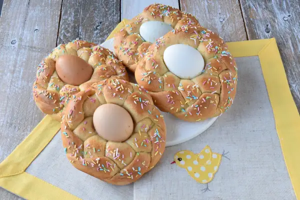Nidi di Pasqua intrecciati, decorati con codette colorate e uova, pronti per la festa.