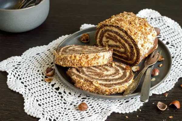 Un delizioso rotolo alla Nutella, ricoperto di granella di nocciole, pronto per essere gustato.