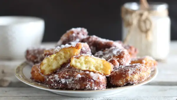 Frittelle di riso ricetta della nonna, dorate e zuccherate, su un piatto. Un assaggio di tradizione.