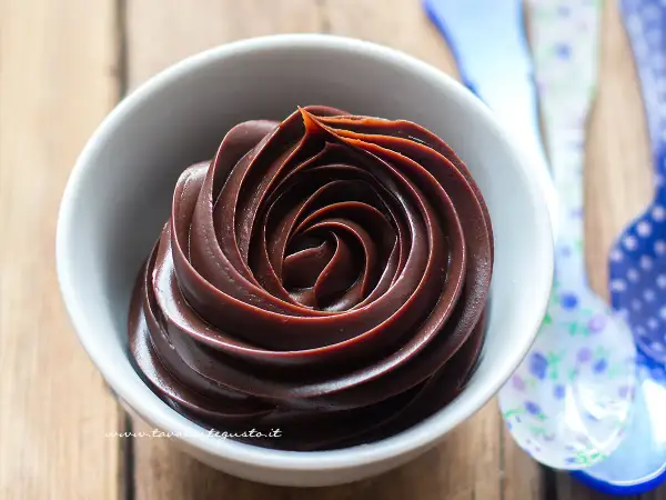 Una spirale perfetta di ganache cioccolato per copertura, lucida e invitante, in una ciotola bianca.