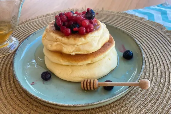 Pancake senza zucchero soffici e dorati, guarniti con frutti di bosco freschi e miele. Un dolce sano e delizioso.