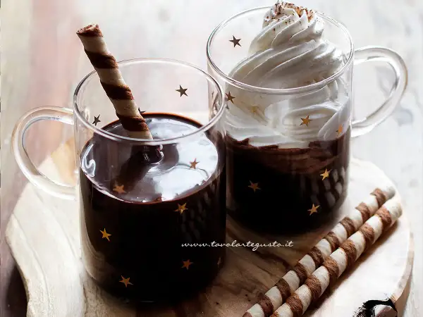 Due tazze di cioccolata calda senza fecola e senza amido, una con cialda, l'altra con panna montata e cacao.